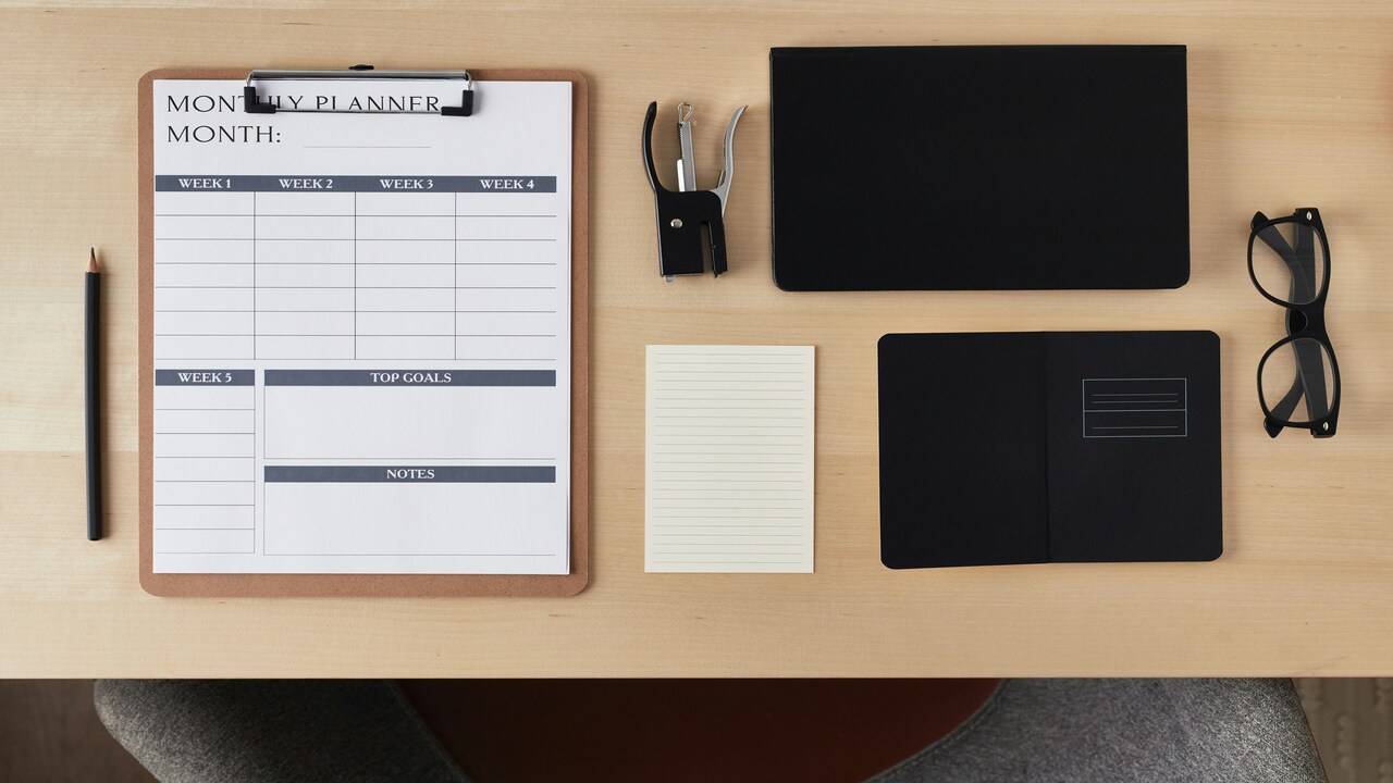 A desk with a calendar, notebook, and more.