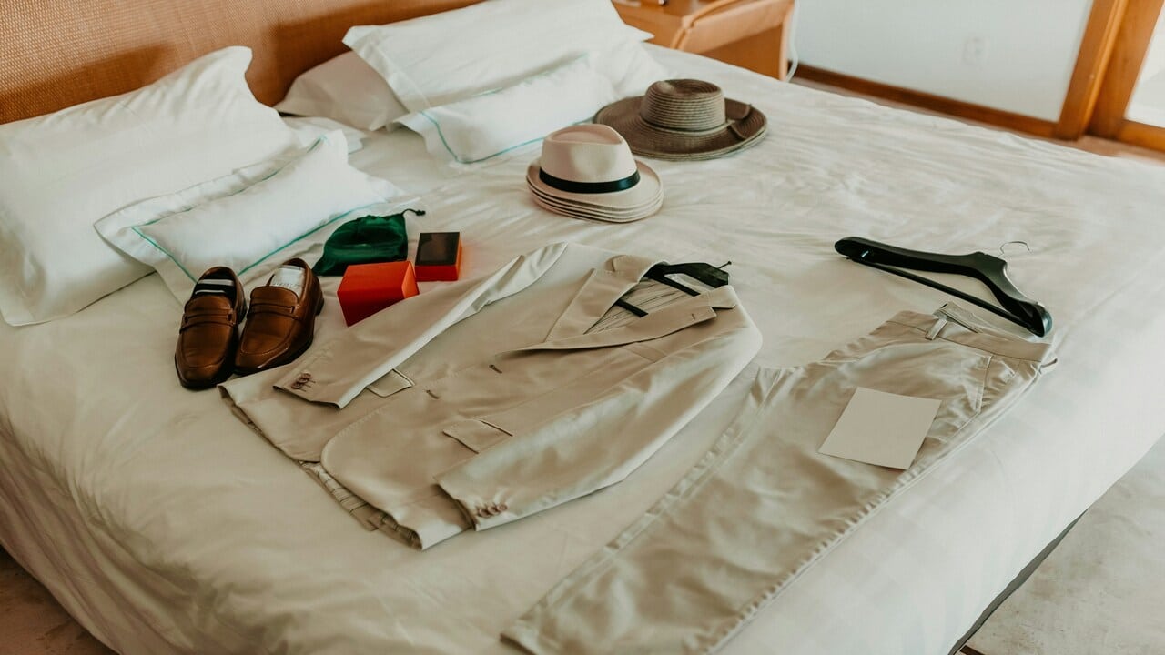 A beige outfit laying on a bed.