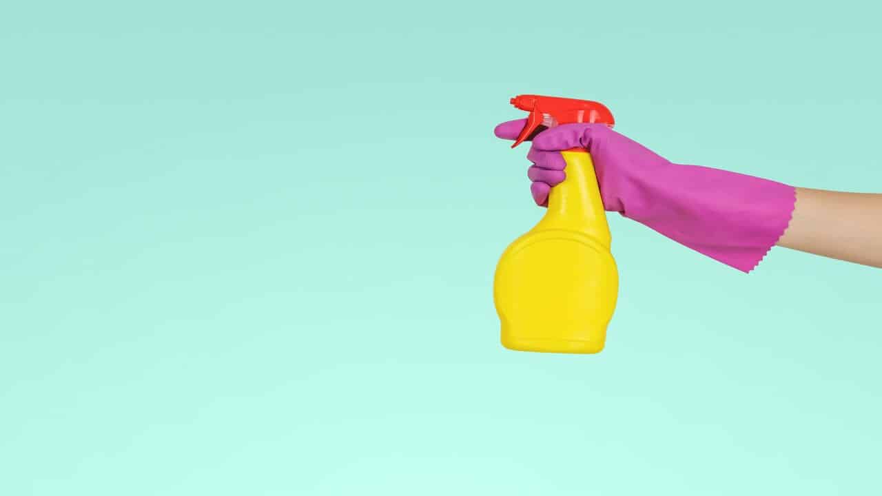 A gloved hand using a cleaning spray bottle.