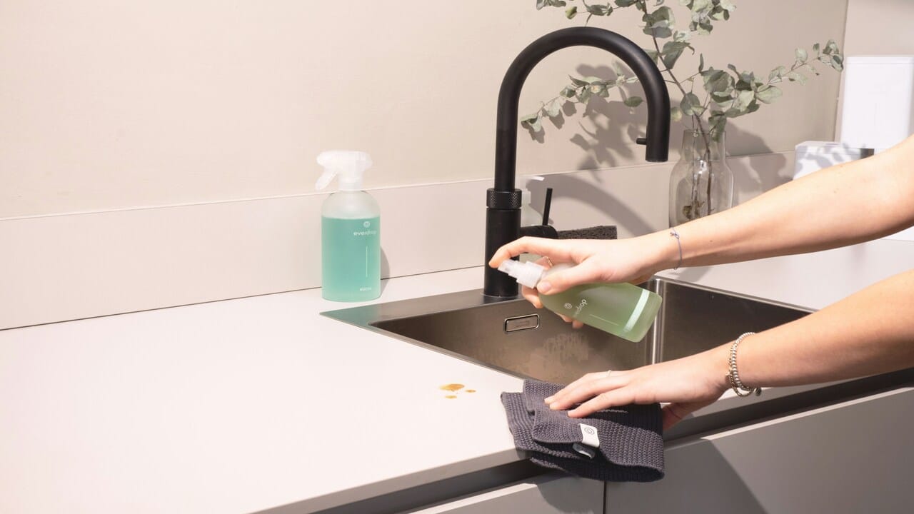 A woman cleaning a kitchen sink.