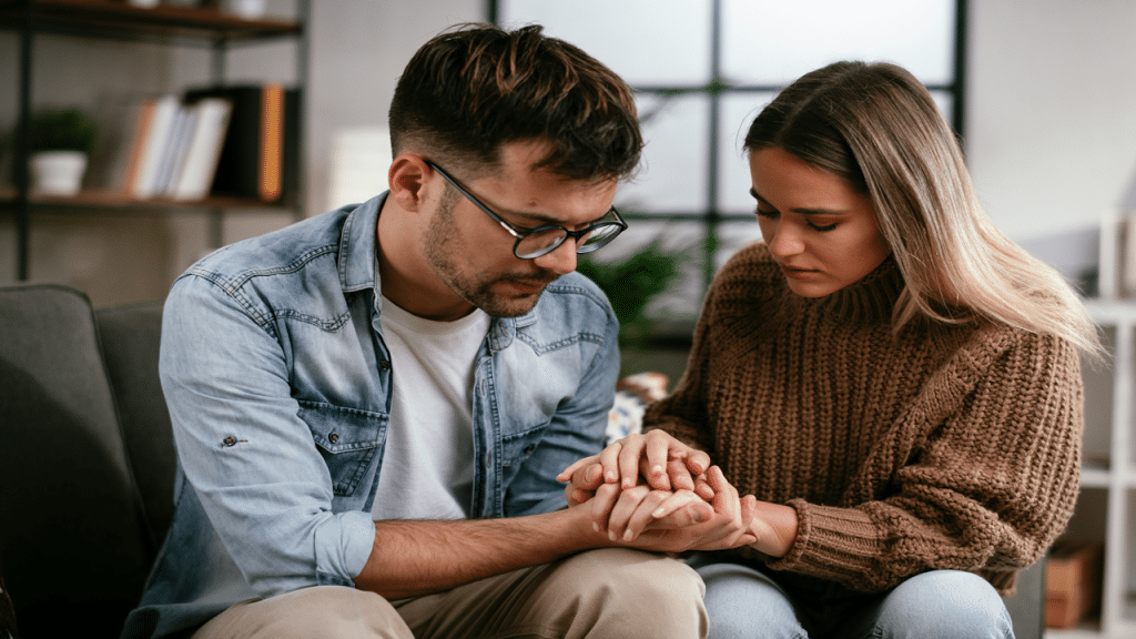 A couple comforts each other and holds hands.