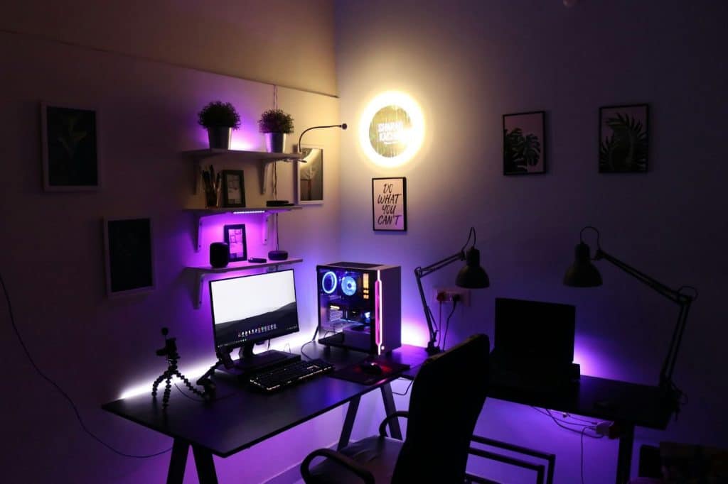 A picture of a gaming set-up with lighting behind the things.