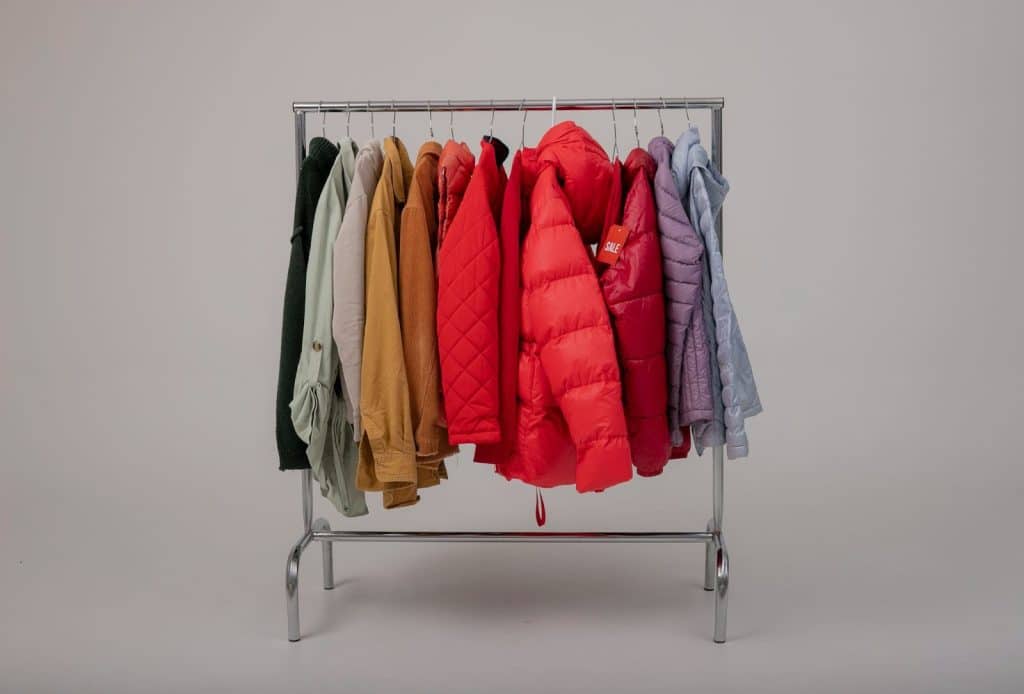 A picture of jacket, coats, and bomber jackets hanging on a rack.