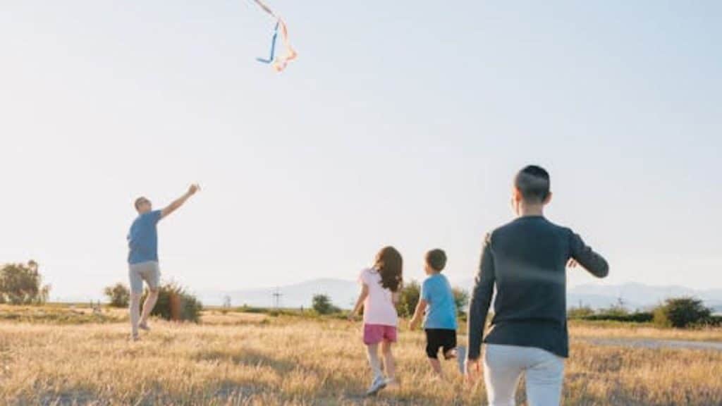 Fathers and kids flying a kite together at a weekend club event.