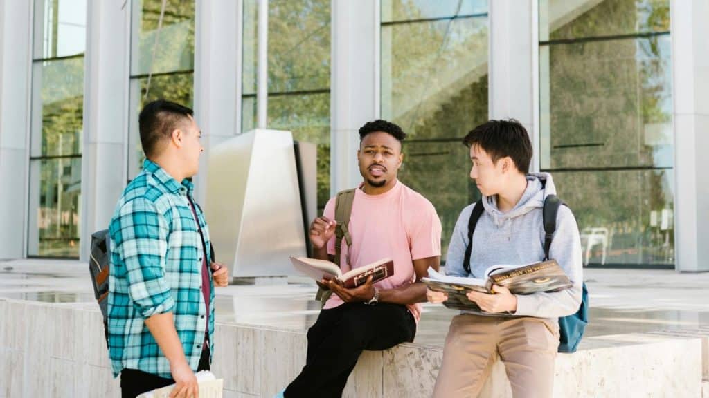 Diverse group of men talking in a modern lounge with books.