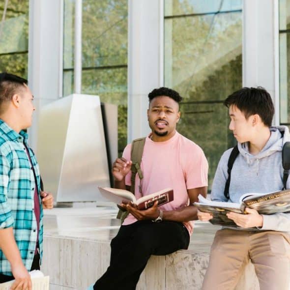 Diverse group of men talking in a modern lounge with books.