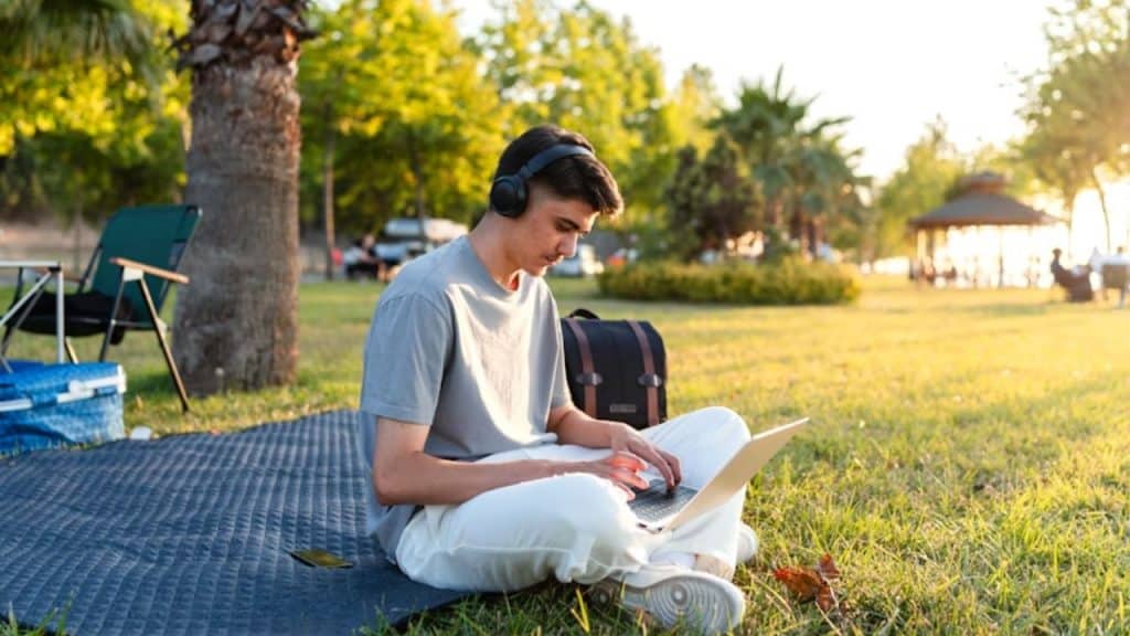 A man sitting alone with headphones, journaling in a park.