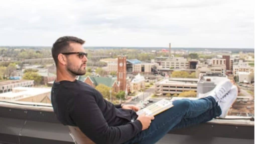 A man in his 30s sits alone on a rooftop, reflecting quietly.