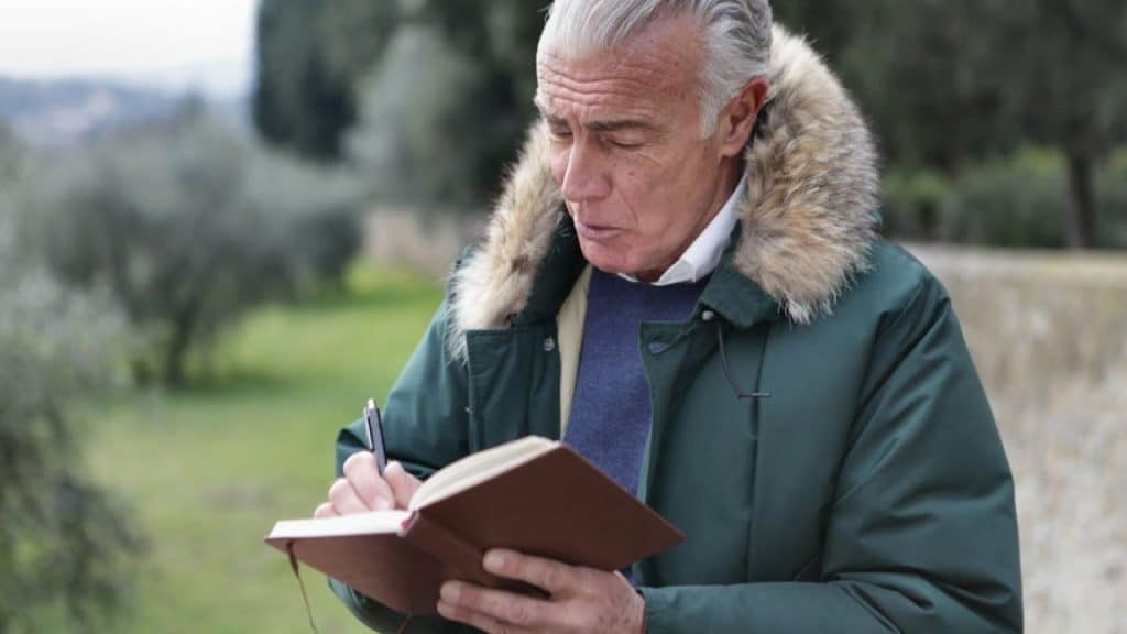 A man journaling or reflecting while sitting alone in a park.