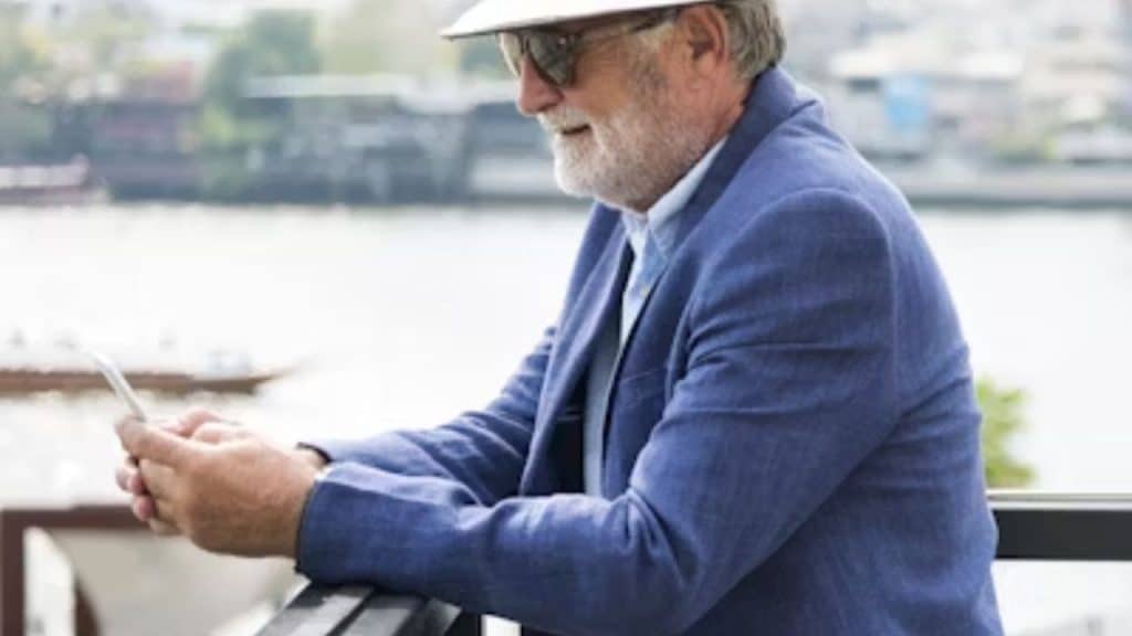 Older man smiling while updating his dating profile on a phone.