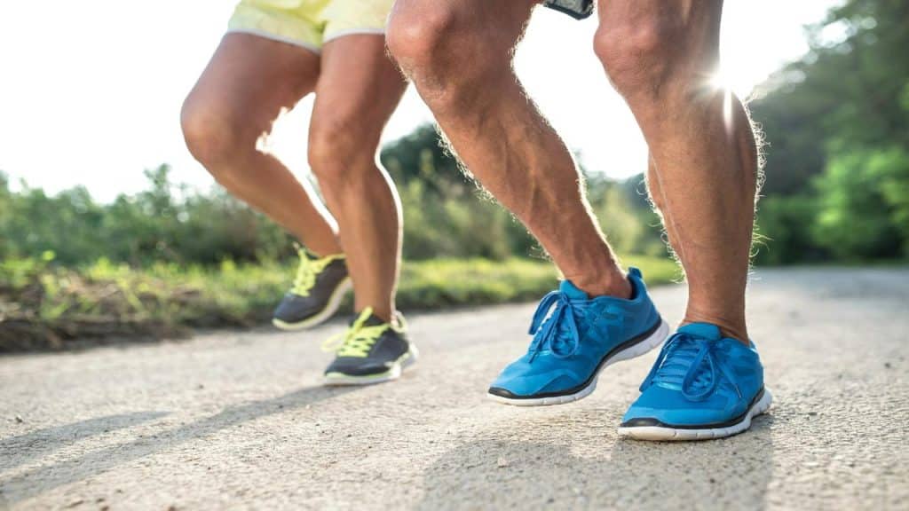 A close-up of two active seniors jogging outdoors on a sunny day, wearing athletic shoes.