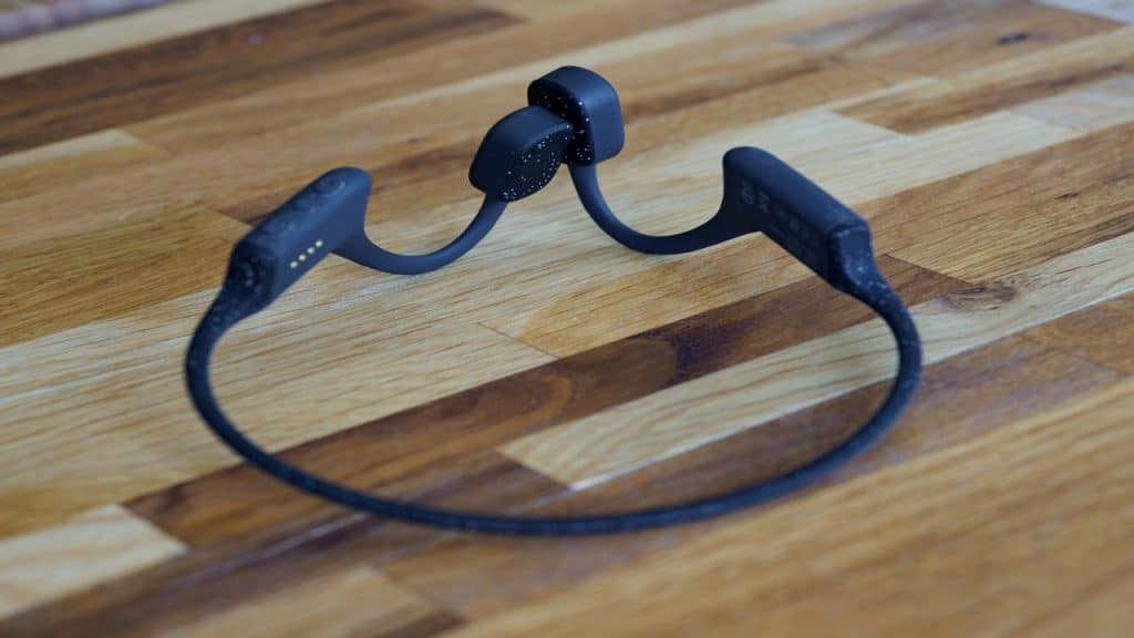 A pair of black bone conduction headphones resting on a wooden surface.