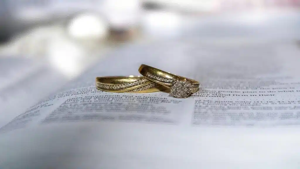 A pair of gold diamond rings resting on an open Bible.