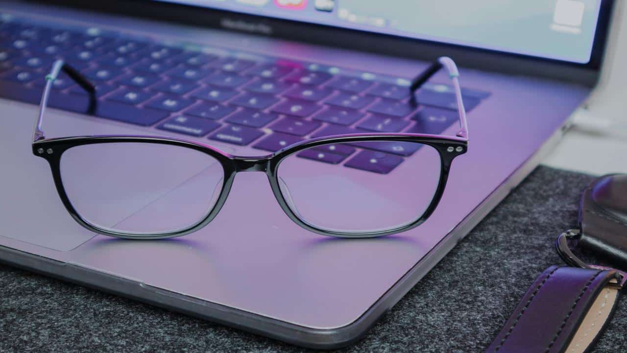 A pair of black-rimmed eyeglasses resting on a laptop keyboard.