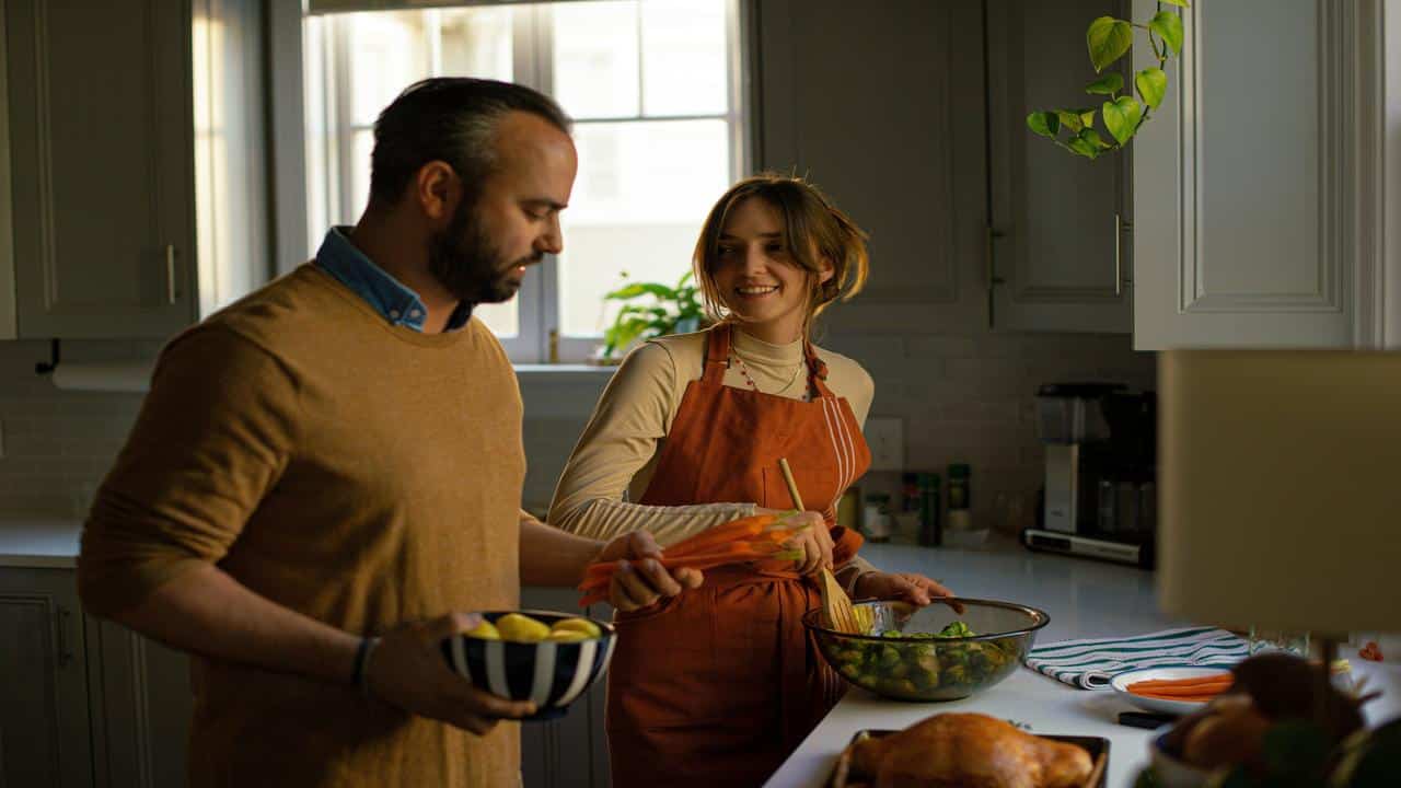 A couple preparing a meal together in a warmly lit kitchen.