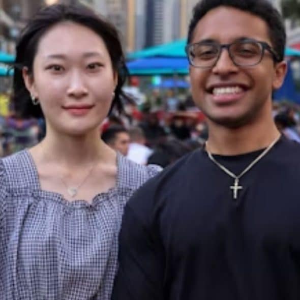 A couple of different ethnicities smiling in a city park.