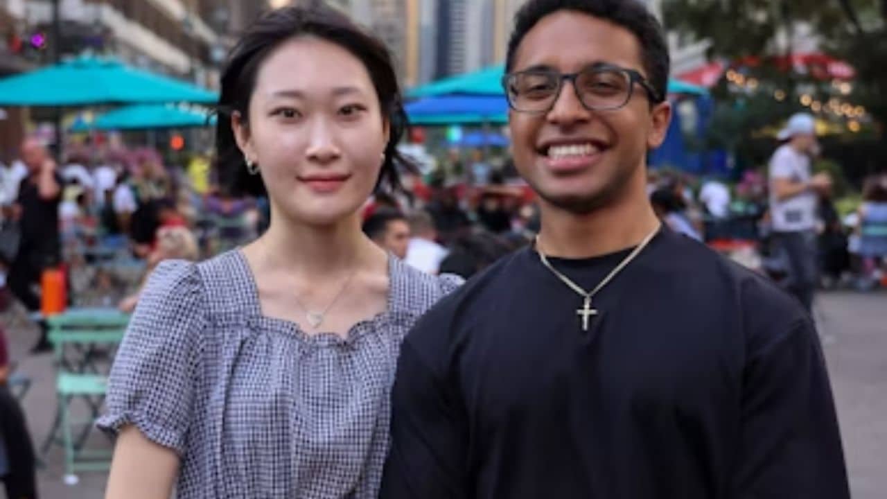 A couple of different ethnicities smiling in a city park.