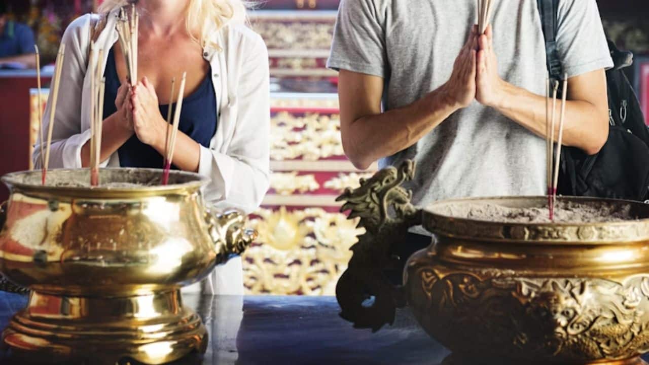 A couple quietly observing a moment of prayer in a temple.