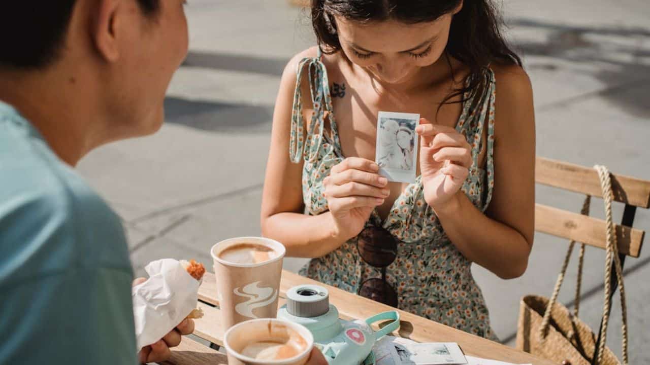 A couple exchanging childhood photos over coffee.