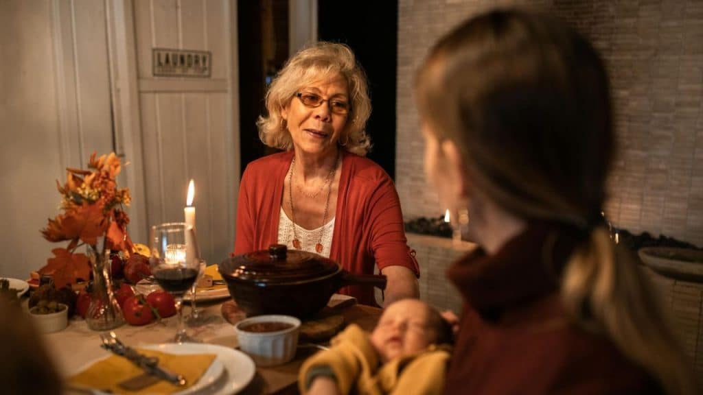 A family, including a baby, sits around a candlelit dinner table.