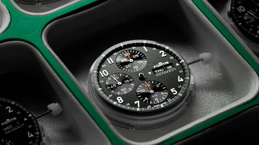 A Fortis Novonaut chronograph watch dial with subdials and a day-date display, placed in a watchmaker's tray.