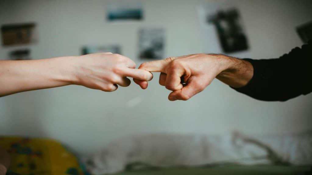 A close-up of a man and woman touching index fingers in a tender gesture.