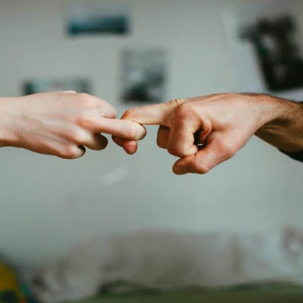 A close-up of a man and woman touching index fingers in a tender gesture.