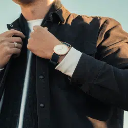 A man adjusting his jacket while wearing a watch.