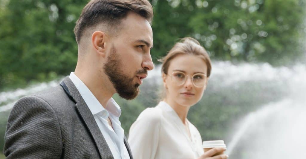 A couple walks silently next to each other, showing emotional distance in body language.