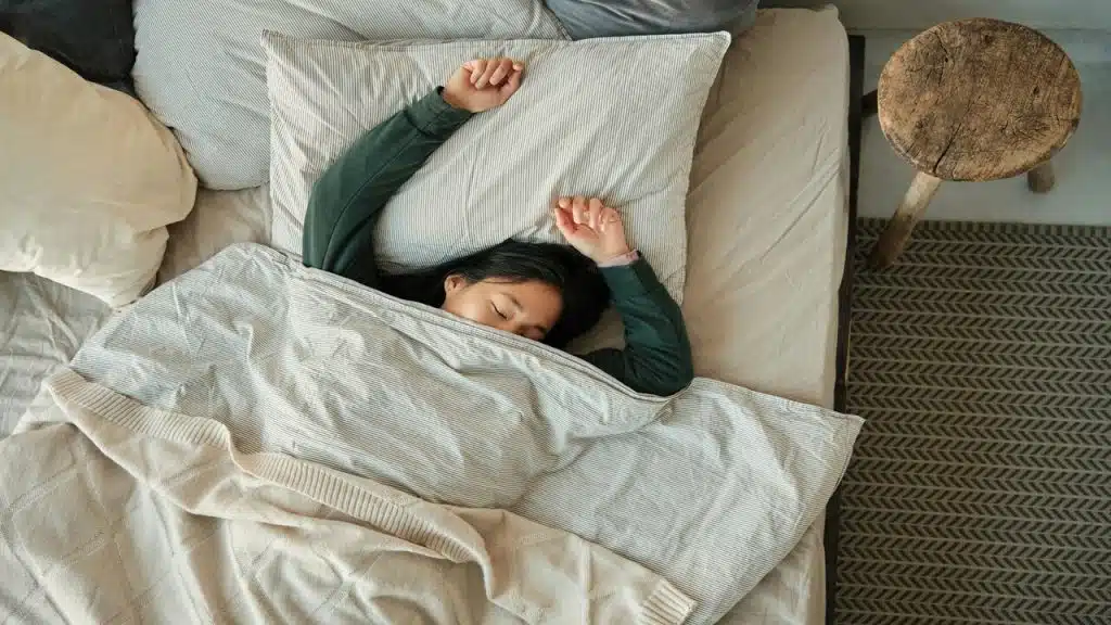 A woman laying in bed under a blanket