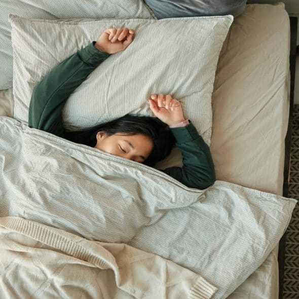 A woman laying in bed under a blanket