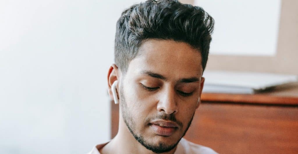 A man writes in a journal with a focused expression, practicing emotional reflection.