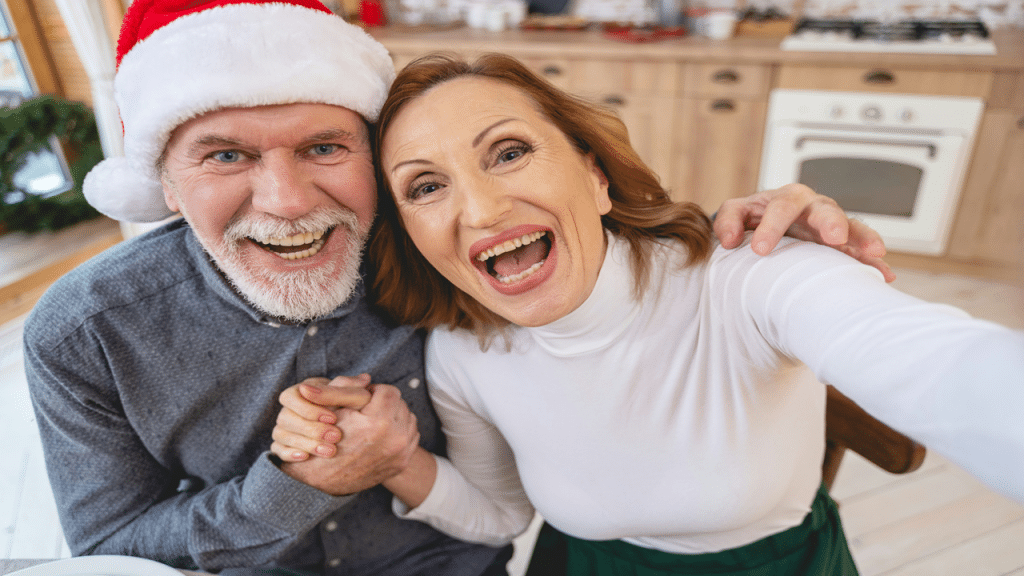 A joyful older couple taking a festive selfie, with one wearing a Santa hat.