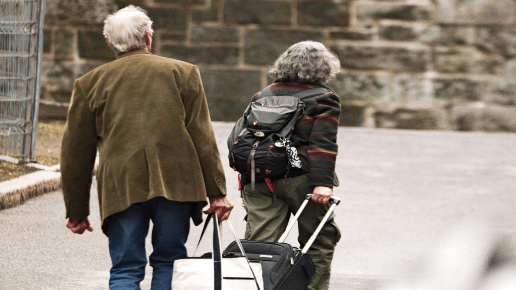 An older couple walks together with luggage, ready for travel.