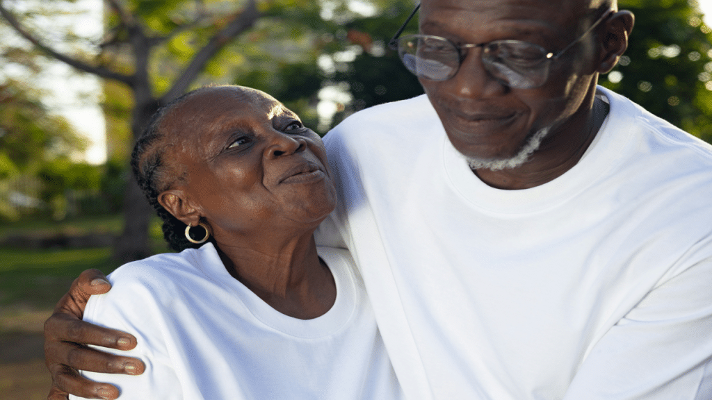 A joyful older couple shares a warm embrace and smiles outdoors.
