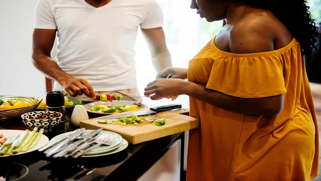 A couple prepares vegetables at a kitchen counter, working together on a meal.