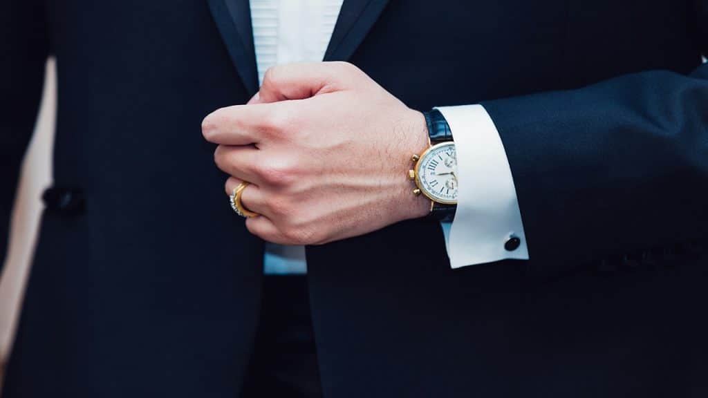 A man wearing a suit with his wristwatch shown.
