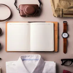 A flat lay of men's fashion accessories and daily essentials on a beige background.