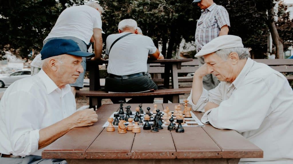 Two old men playing chess outdoors.