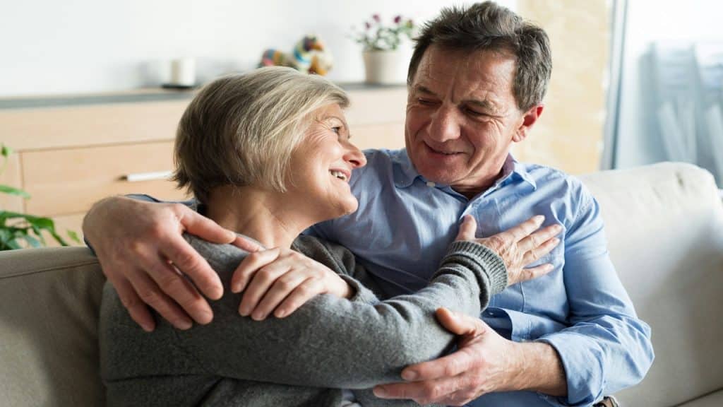Husband and wife smiling and holding each other in the living room