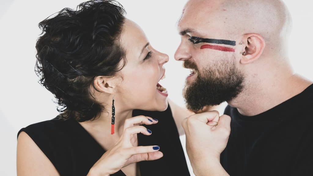 A woman jokingly laughs at her angry partner.
