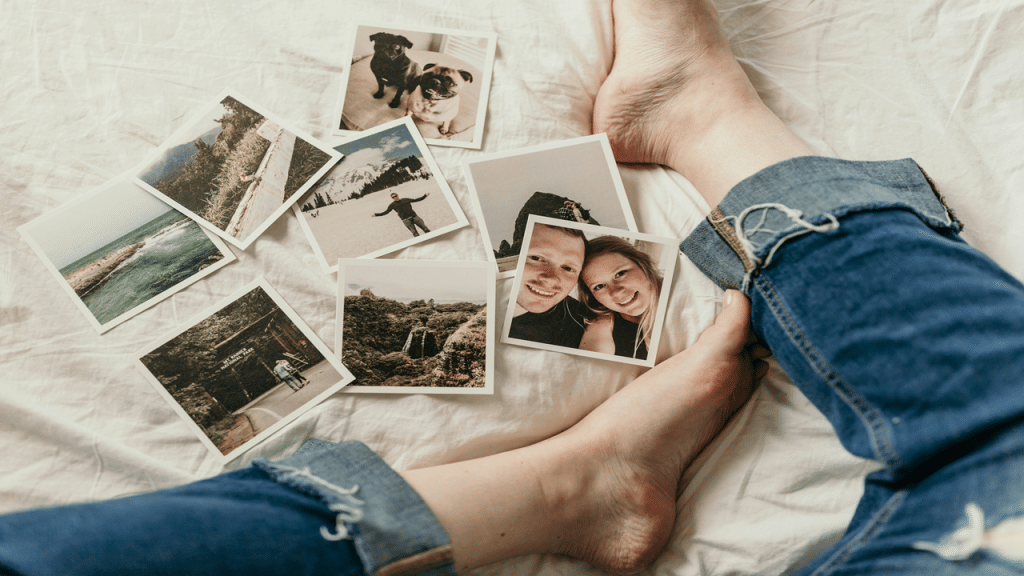 A person sitting on a bed surrounded by printed photos.