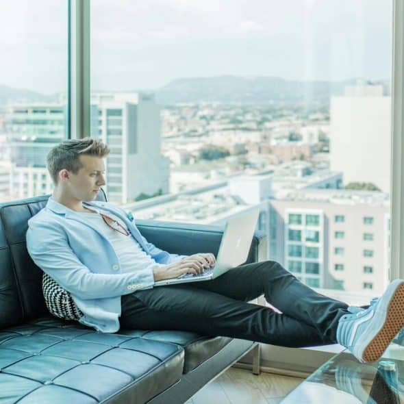 Man sitting on sofa while using laptop