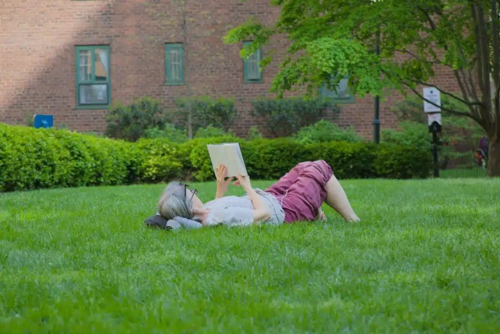 A lady reading comfortably on a grass