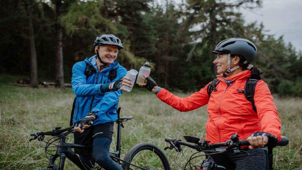 A happy couple enjoying the outdoors while riding a bike together.