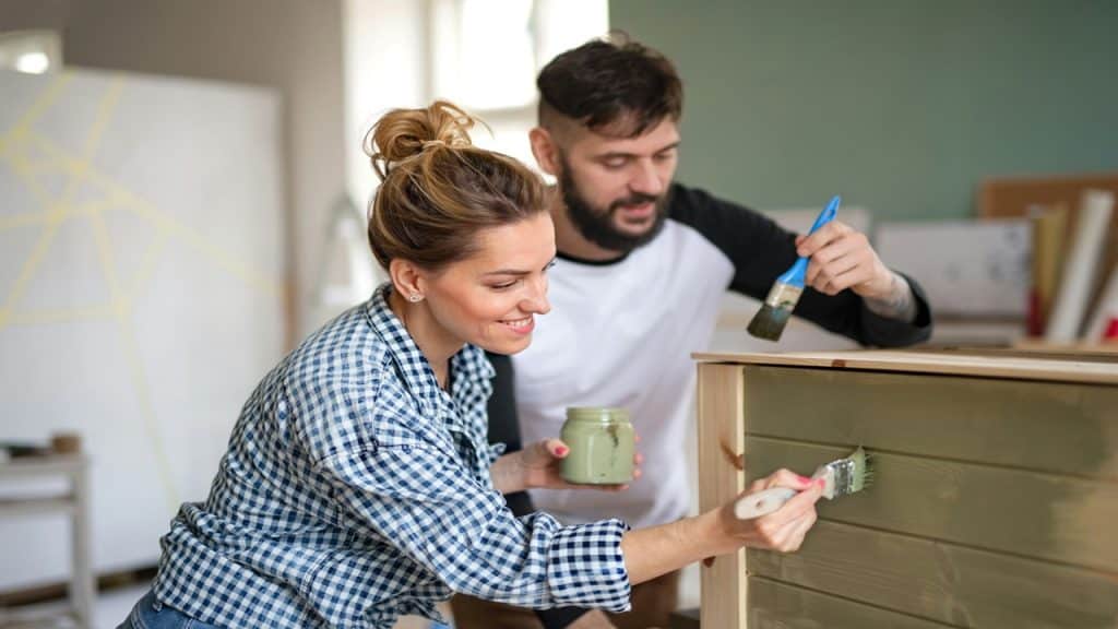 A couple painting a wardrobe together.
