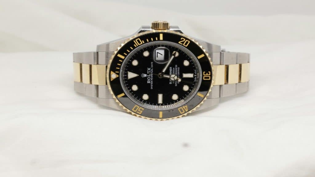 A photo of a Rolex resting sideways on a cloth surface.