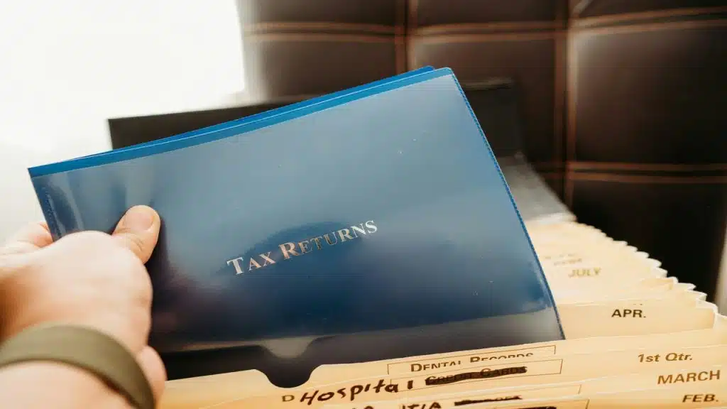A person holding a blue envelope saying “tax returns”