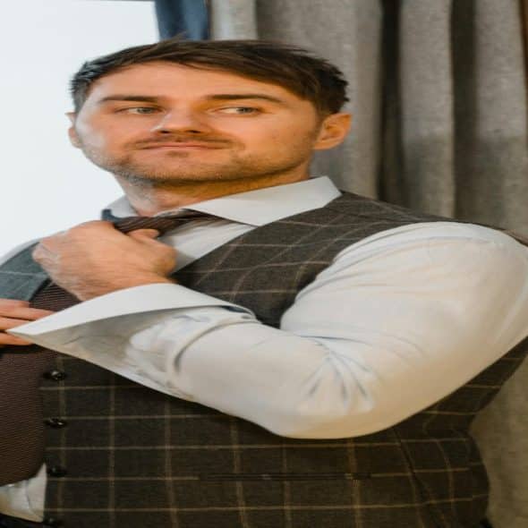 A confident man tying his tie with exuding calm energy and quiet charisma.