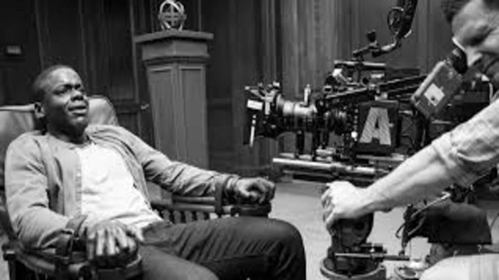 A Cameraman filming an actor on a couch who is looking scared.
